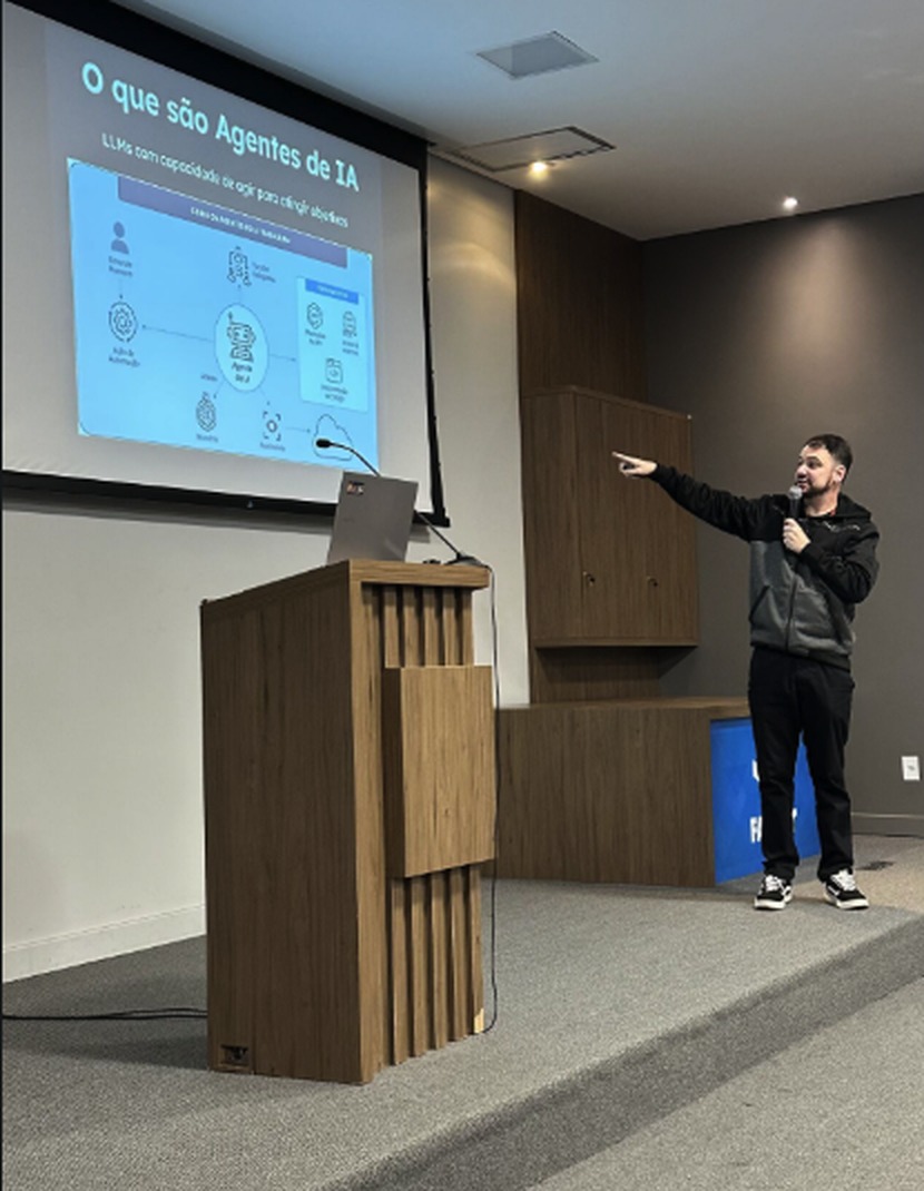 Diego Candido palestrando sobre agentes de IA com ferramentas low-code no meetup Devs do Paranhana, no auditório da Faccat